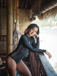 Side view of Woman wearing Black Long Sleeve Surf Swimsuit in surf shack| The Sulawesi Midnight 