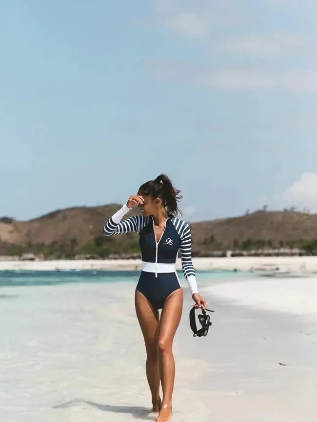woman walking on beach in Long Sleeve swimsuit in navy and white stripe| The Sulawesi in Nautical front view