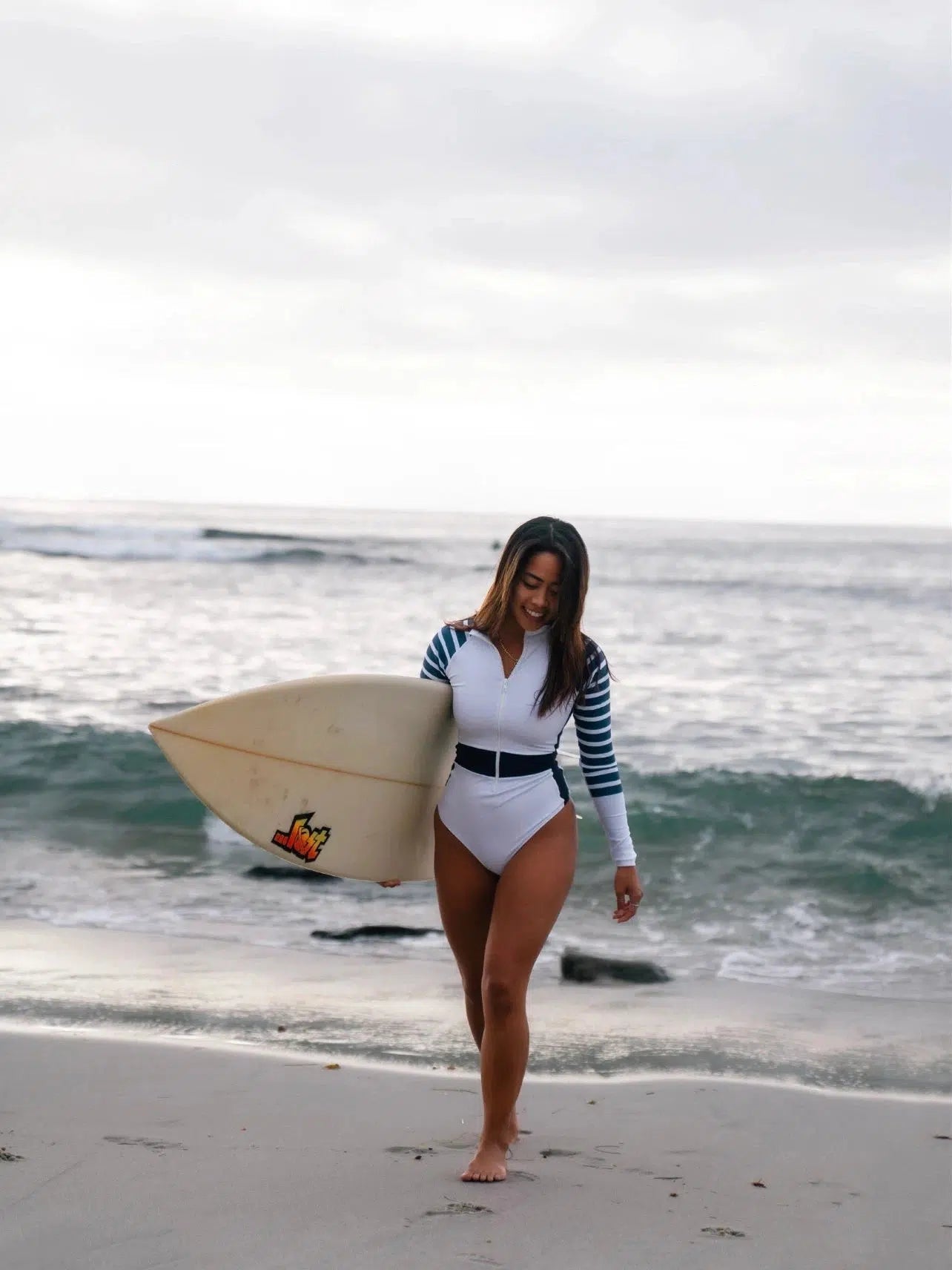 surfer at beach wearing Long Sleeve One Piece Swimsuit | The Sulawesi Snow and Navy