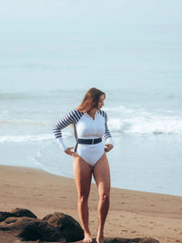 lady at beach wearing white Long Sleeve One Piece Swimsuit | The Sulawesi Snow and Navy